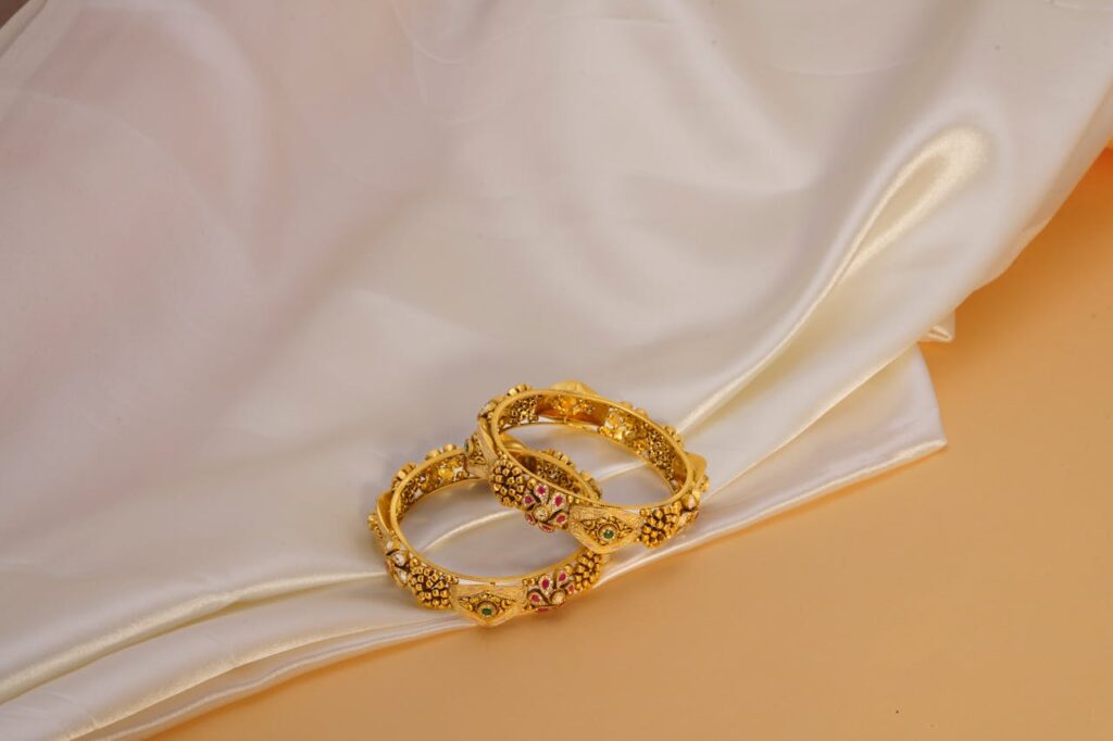 Luxurious gold bangles on a satin backdrop, showcasing intricate jewelry design.