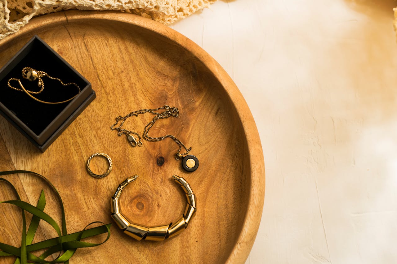 A selection of gold jewelry elegantly arranged on a wooden tray.
