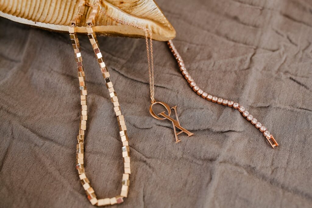 Elegant gold necklaces and diamond bracelet on gray fabric for a chic lifestyle look.
